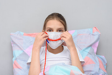 Image showing Girl shows a smile on her face made of threads, doing knitting at home in self-isolation mode