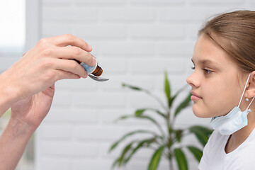 Image showing The doctor in the hospital pours medicine for a sick girl in a spoon