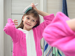 Image showing Girl combing her hair in the bathroom early in the morning