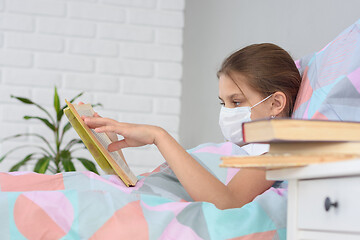 Image showing A girl with influenza is reading a book, books are on the nightstand in front of her, focusing on the girl