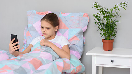 Image showing Girl communicates by video calling while lying in bed with a mobile phone