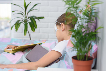 Image showing The sick girl lies in bed and fell asleep reading a book