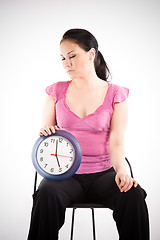 Image showing Tired businesswoman holding a clock