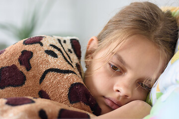 Image showing Girl slowly wakes up, lying in bed and covered with an old blanket