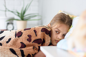 Image showing Girl lying in bed covered with an old bedspread