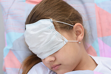 Image showing The girl fell asleep in bed, on her face and eyes she pulled on a medical mask, close-up