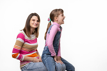 Image showing On the mothers lap, a daughter sits and laughs joyfully turning to the side