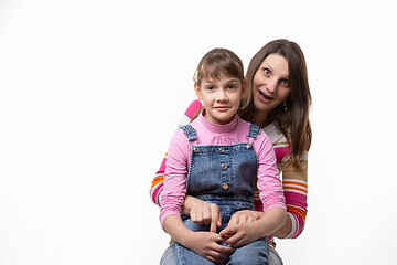 Image showing A girl sits on her mothers lap and stares in surprise at the frame