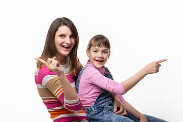 Image showing Joyful mom and daughter point finger in different directions, isolated on white background