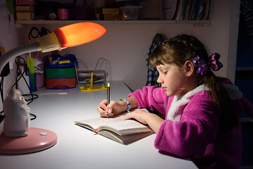 Image showing A girl does homework late at night