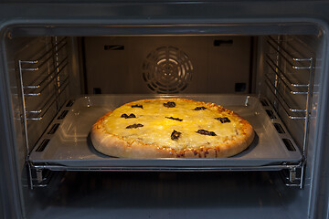 Image showing Baking quattro formaggi pizza in oven with open door.