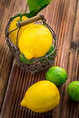 Image showing Organic lemons and limes in a basket on wooden background