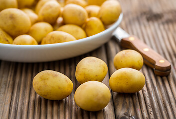 Image showing Fresh organic small potatoes in bowl with knife on wooden background