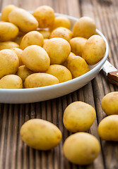 Image showing Fresh organic small potatoes in bowl with knife on wooden background