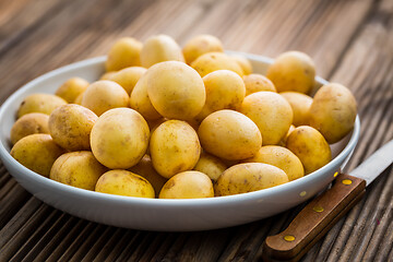 Image showing Fresh organic small potatoes in bowl with knife on wooden background