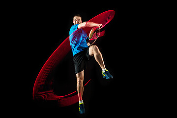 Image showing one caucasian man playing tennis player on black background