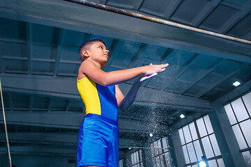 Image showing beautiful boy is engaged in sports gymnastics on a parallel bars