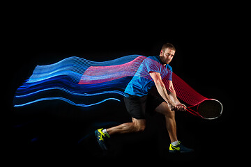 Image showing one caucasian man playing tennis player on black background