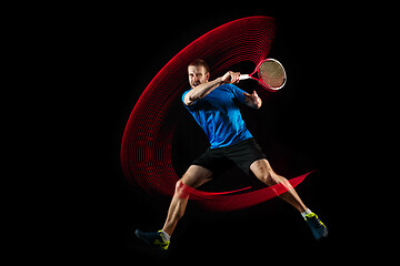 Image showing one caucasian man playing tennis player on black background