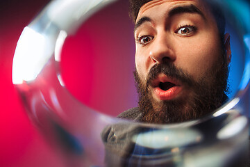 Image showing The surprised young man in party clothes posing with glass of wine.