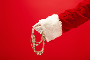 Image showing Hand of Santa Claus holding a toy Christmas decorations on red background