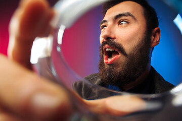 Image showing The surprised young man in party clothes posing with glass of wine.