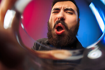 Image showing The surprised young man in party clothes posing with glass of wine.