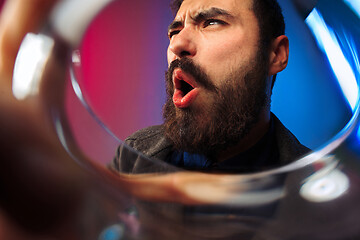 Image showing The surprised young man in party clothes posing with glass of wine.