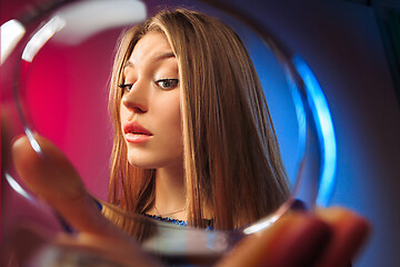 Image showing The surprised young woman in party clothes posing with glass of wine.