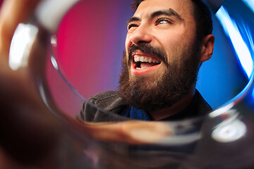 Image showing The surprised young man in party clothes posing with glass of wine.