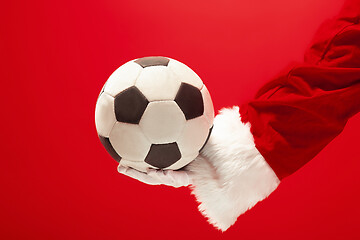 Image showing Santa Claus holding a football ball isolated on red background