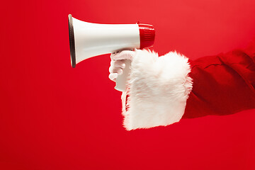 Image showing Hand of Santa Claus holding a megaphone on red background