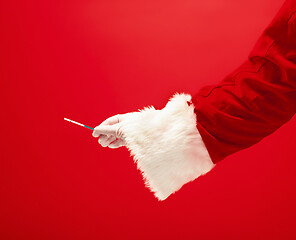 Image showing Hand of Santa Claus holding a pregnancy test on red background