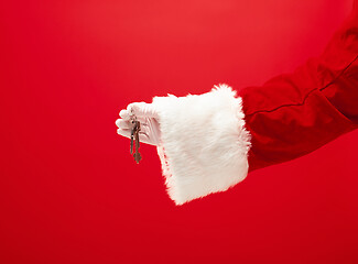 Image showing Hand of Santa Claus holding a gift on red background