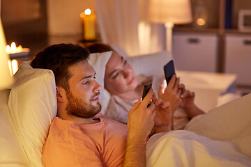 Image showing couple using smartphones in bed at night