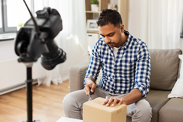 Image showing male video blogger opening parcel box at home