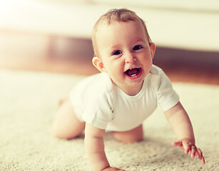 Image showing little baby in diaper crawling on floor at home