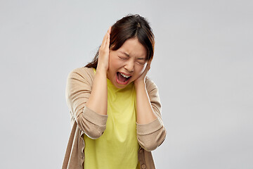 Image showing stressed asian woman closing ears and screaming