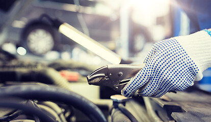 Image showing mechanic man with pliers repairing car at workshop