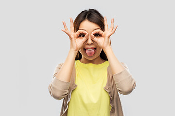 Image showing smiling asian woman looking through finger glasses