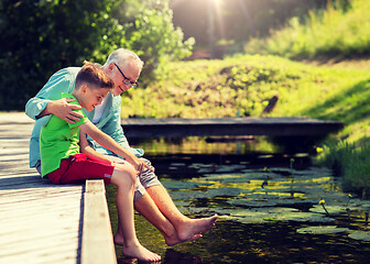 Image showing grandfather and grandson sitting on river berth