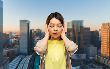 Image showing asian woman closing ears by hands in tokyo city