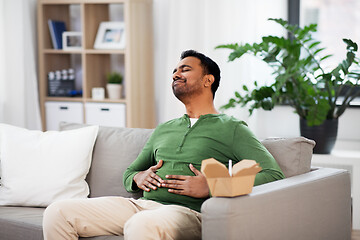 Image showing pleased indian man eating takeaway food at home
