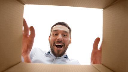 Image showing smiling man taking something out of parcel box