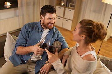 Image showing happy couple drinking red wine at home in evening