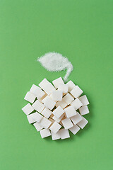 Image showing Handmade apple from sugar cubes and leaf on a green background.