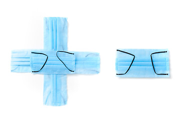 Image showing Sign plus and minus made from protective medical masks on a white background.