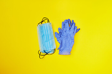 Image showing Two piles from medical masks and protective gloves on a yellow background.