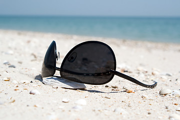 Image showing The black sunglasses lying on a beach