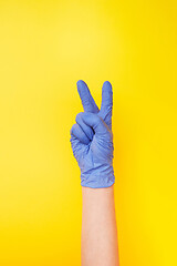 Image showing Sign victory made female\'s hand in rubber protective glove.